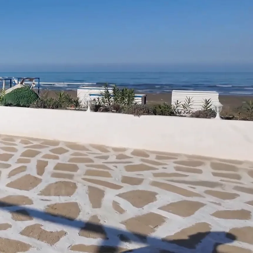 A paved terrace by the sea: a white parapet and the beach (2024)